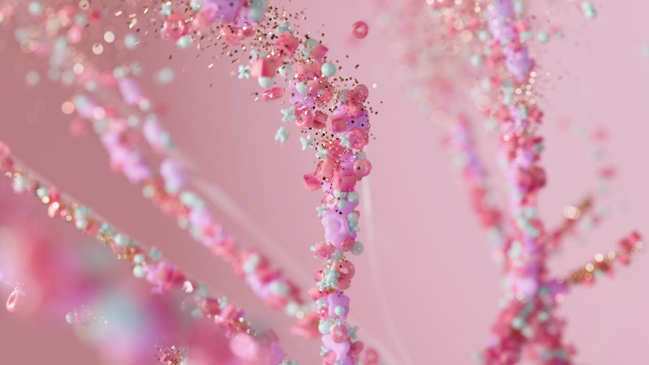 gallery-1 Close-up of pink and gold sparkling beads on a pastel pink background, creating a dreamy and abstract visual.