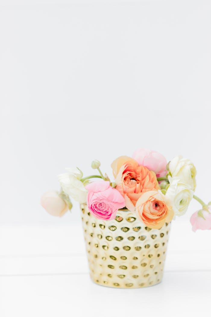 A colorful bouquet arrangement in a stylish gold flower pot with ample copy space.