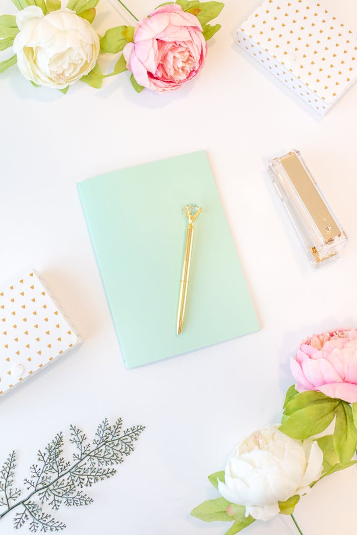 about-01 Stylish flat lay of pastel notebook, pen, and flowers on a white background. Perfect for feminine office themes.