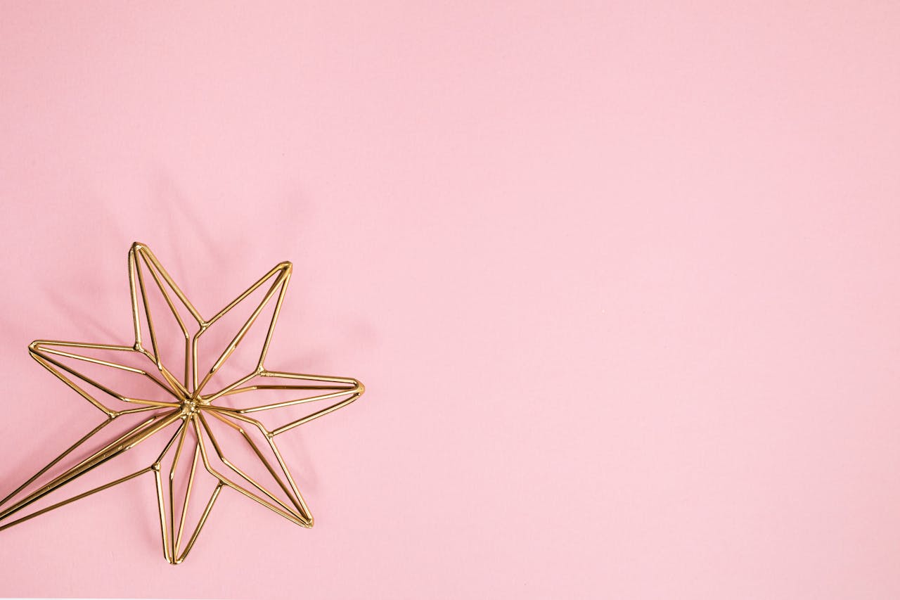 Elegant gold wire star decor on a soft pink background with copy space.